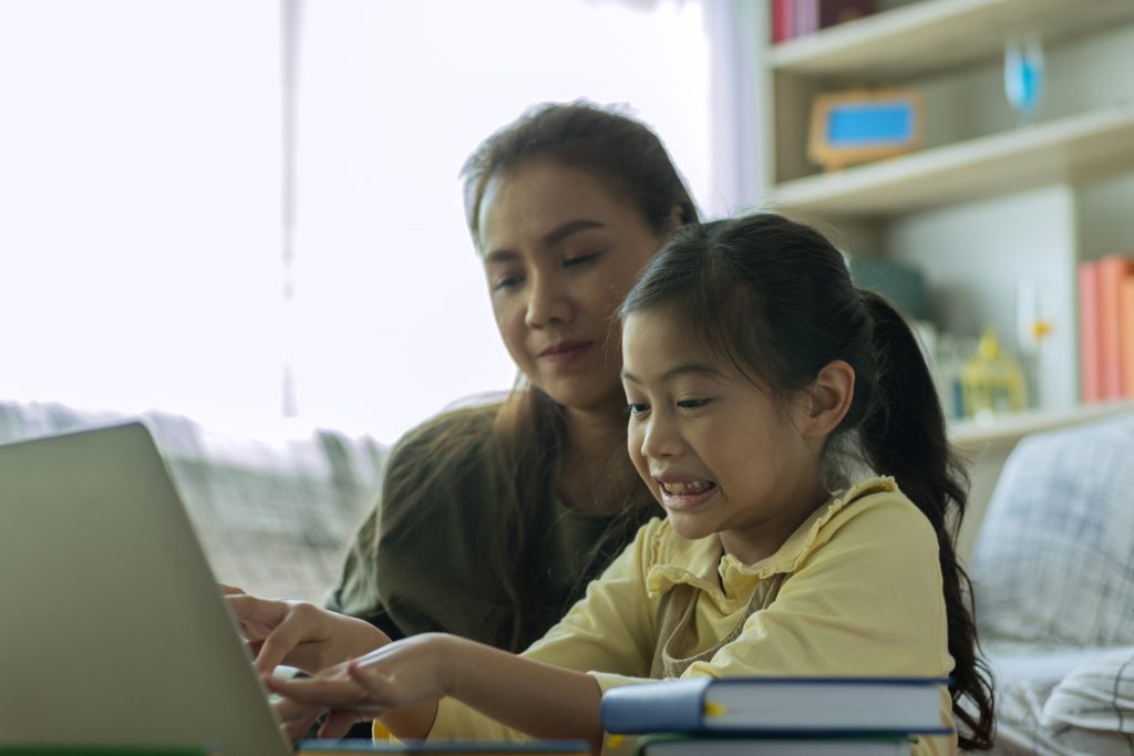 A parent and a child sit in front of a computer
