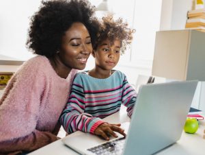 A parent smiles as a student uses the computer